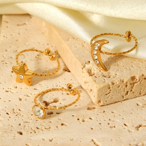 Detailed view of three gold-plated celestial rings with stars and moon on silk fabric