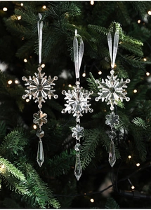 Detail of transparent acrylic snowflake and teardrop ornaments hanging on a Christmas tree