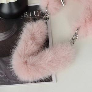Close-up of pink fluffy plush strap and silver metal chain on a minimalist shoulder bag