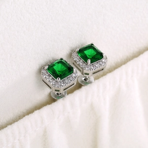 Macro view of square emerald zircon earrings with halo diamond setting and silver posts