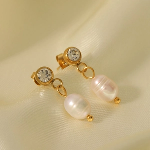Eleganti orecchini di perle in acciaio dorato con zircone su sfondo di seta