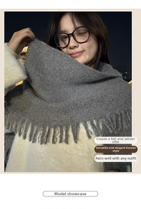Detail of grey knitted scarf with long fringe tassels showing thick warm texture