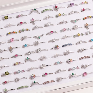 Detailed grid of colorful zircon flower and pearl rings in a velvet jewelry box