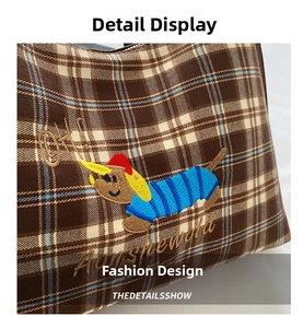 Close-up of brown checkered tote bag with colorful cartoon dachshund embroidery