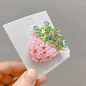 Macro detail of handmade beaded strawberry hair clip with pink sequins and pearls