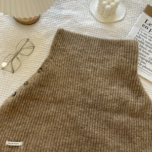 Detailed view of brown ribbed knit vest featuring side buttons and Hilldi Plan brand tag