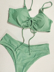 Detail of sage green bikini top with halter neck ties and metallic strap adjusters