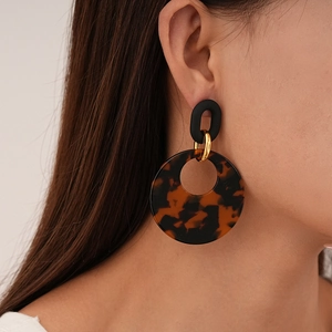 Detail of tortoise shell resin hoop earring on model showing vintage geometric style