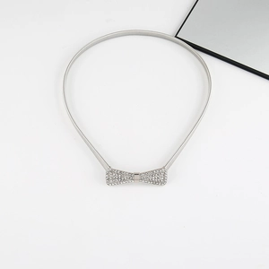 Detail of silver spring belt featuring a sparkling rhinestone bow buckle on white background