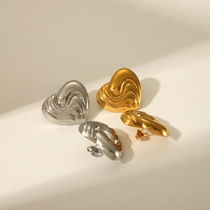 Dettaglio di orecchini a cuore con texture metallica liquida in oro e argento