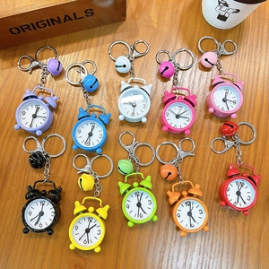 Decorative colorful mini alarm clock keychains with bells on a rustic wooden background
