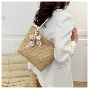Détail du sac cabas en paille tressée avec anses en corde et nœud en foulard de soie