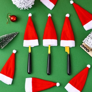 Close-up of mini red velvet Christmas hats used as cutlery holders for gold and black knives