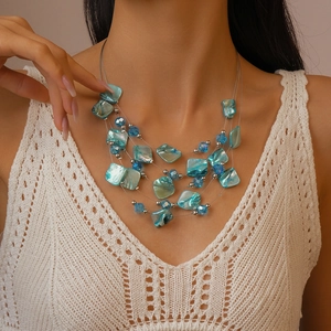 Detail view of multilayer blue beaded necklace with irregular shell charms for beach style