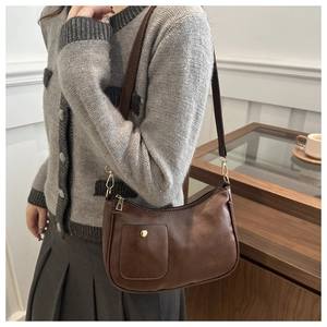 Detail shot of vintage dark brown PU leather shoulder bag with gold hardware on a model