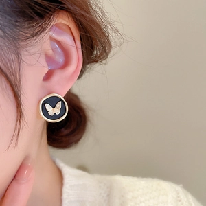 Detailed view of vintage gold butterfly earrings with black enamel on a female model