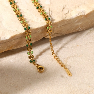 Gold 18K stainless steel bracelet featuring green enamel olive leaves on a stone background