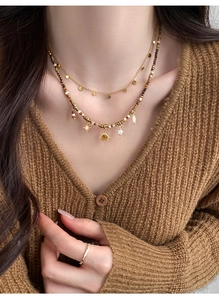 Detail of layered gold necklace with sun star pendants and brown tiger eye beads