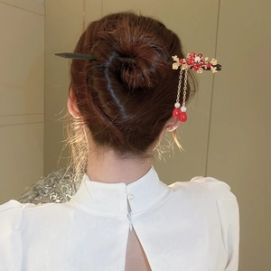 Detail of vintage flower hair stick with red beads and pearls worn in a bun hairstyle