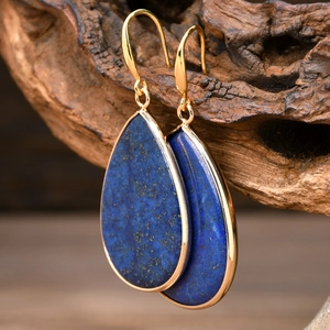 Detailed view of teardrop lapis lazuli earrings on a textured wooden background