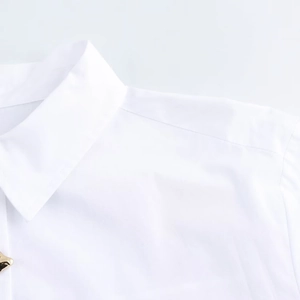 Detail view of the lapel collar and shoulder seam on a white long-sleeved shirt