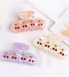 Detailed view of acrylic cherry hair claws with rhinestones in pink, beige and purple colors