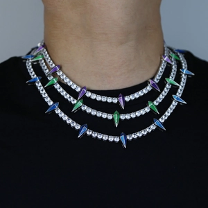 Close-up of stacked silver tennis chains with colorful geometric spike pendants