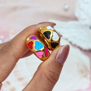 Close-up of golden rings with black, white, and colorful enamel heart patterns