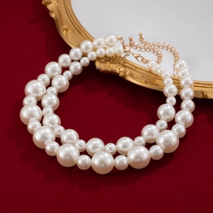Close-up of double layer pearl necklace with gold clasp on vintage mirror and red background