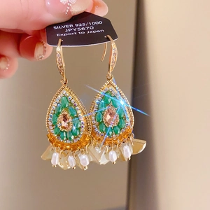 Macro shot of ethnic drop earrings with champagne crystals and pearl tassels on silver hook