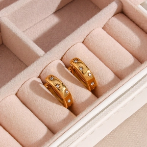 Gold star-engraved hoop earrings with white zircon on pink velvet jewelry box