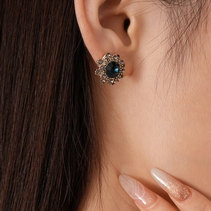 Detailed macro view of a vintage floral earring featuring a sapphire-blue center gemstone
