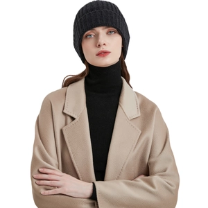 Minimalist winter knit beanie hat in black shown on a fashion model with wool coat