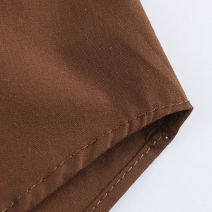 Detail of brown cotton poplin fabric with clean single-stitch sewing and wide cuff design