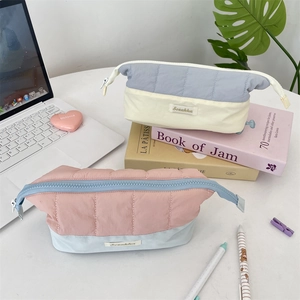Detailed view of quilted color-block pencil case on a desk with a laptop and plants