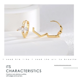 Detail of elegant gold-plated floral earrings with marquise-cut zircon stones on white stone