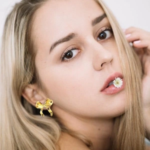 Elegant gold brass bow stud earrings on a female model with a polished finish