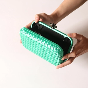Elegant green woven satin clutch bag with glossy texture and black twist lock closure