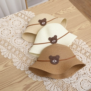 Close-up of three woven straw sun hats for kids with cute bear patches on lace decor