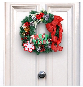 Christmas wreath with red bow and Merry Christmas sign hanging on a white door