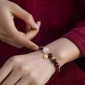 Close-up of red beaded Christmas bracelet with Pingan gold pendant and white jade bead