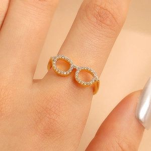 Mini gold glasses-shaped open ring with pavé white zircons on model's finger