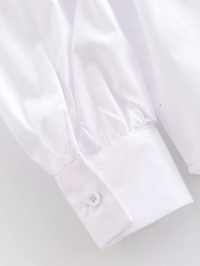 Détail de la manche d'une chemise en coton blanc avec poignet à bouton et plis