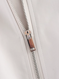 Macro shot of high-quality metal zipper and light grey twill fabric on a flight jacket
