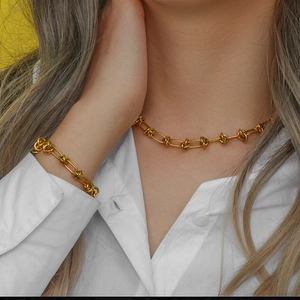 Detailed view of golden multi-knot chain necklace and bracelet set on a model