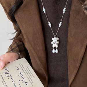 Collier de perles avec pendentif ours floqué et nœud en cristal sur manteau marron