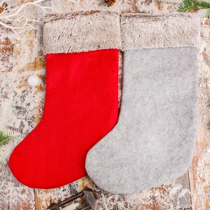 Red and grey Christmas stockings with plush reindeer design on snowy wooden background