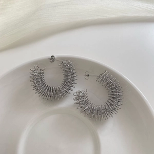 Orecchini a cerchio argento a molla su vassoio in ceramica bianca con tulle decorativo
