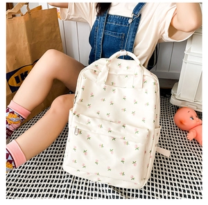 Detailed view of cream floral print backpack with front pocket and durable canvas material