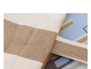 Close-up of fine stitching on a beige and brown striped canvas tote with durable straps